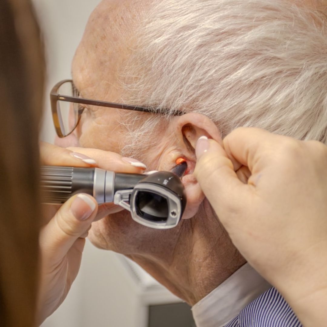 Audiologist examining an older patient's ear using an otoscope at Vons Hearing Clinic